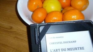 Des mandarines et une liseuse avec en couverture, le livre de Chrystel Duchamp, L'Art du meurtre.