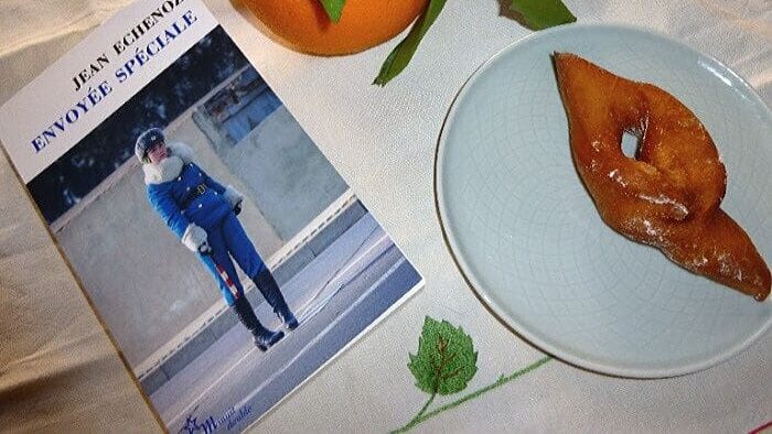 Livre de poche "Envoyée spéciale" de Jean Echenoz à côté d'une bugne et d'une orange