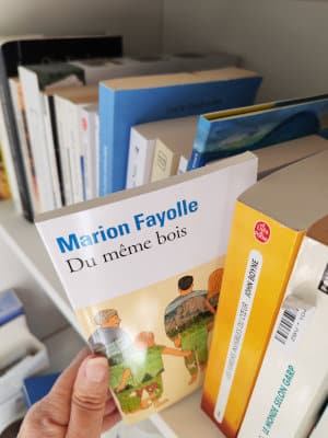 Une main sort de la bibliothèque le livre de Marion Fayolle, Du même bois