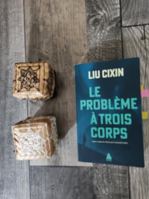 Le livre de Liu Cixin, Le problème à trois corps. A côté deux petites boîtes asiatiques