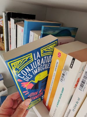Une main sort de la bibliothèque, le livre de John Kennedy Toole, La conjuration des imbéciles