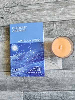A côté d'une bougie, le livre de Frédéric Albergel, Après la neige, posé sur un parquet