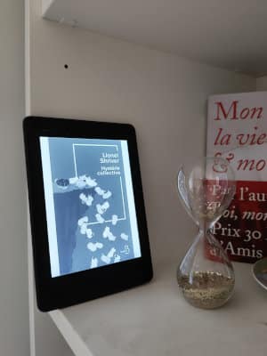 Liseuse posée sur une étagère avec la couverture du livre de Lionel Shriver, Hystérie collective