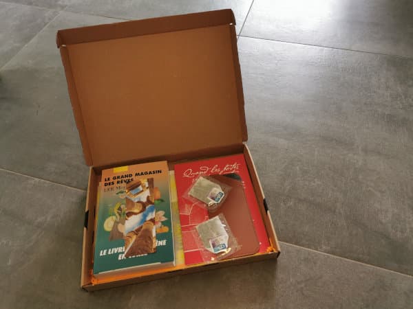 Une box Kube ouverte sur son contenu : le livre de Mi-ye Lee, Le grand magasin des rêves, un carnet, un étui à lunettes et deux sachets de thé