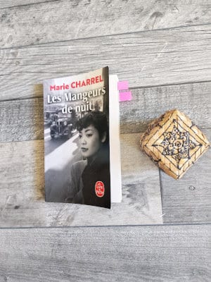 A côté d'une boîte au décor asiatique, le livre de Marie Charrel, Les mangeurs de nuit, posé sur un parquet.