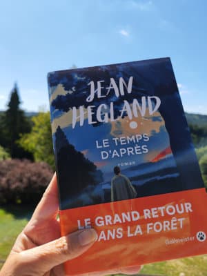 Une main tient, devant des arbres, le livre de Jean Hegland, Le temps d'après