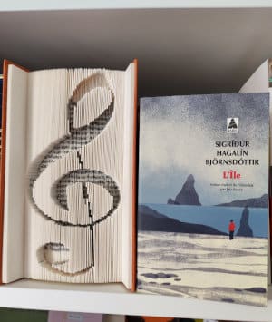 Livre de Sigríður Hagalín Björnsdóttir, L'île, à côté d'un livre dont la tranche a été découpée en clé de sol