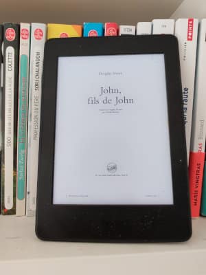 Liseuse posée sur une étagère, ouverte sur la page de garde du livre de Douglas Stuart, John, fils de John