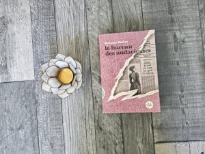 Le livre de Mélanie Sadler, Le bureau des audacieuses posé sur le sol. A côté, un photophore en forme de fleur