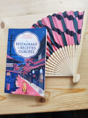 Posé à côté d'un éventail, le livre de Hisashi Kashiwai, Le restaurant des recettes oubliées